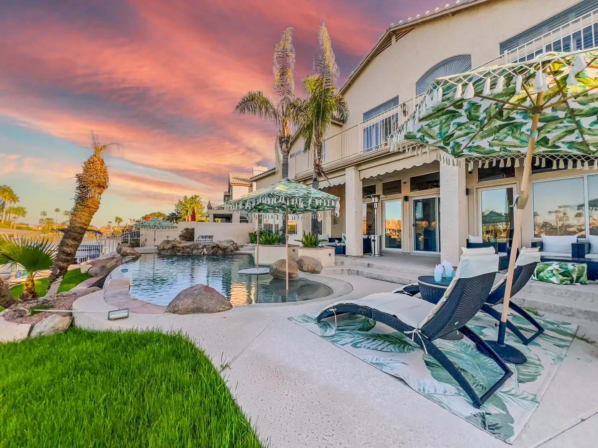 An elegant exterior shot of a sparkling swimming pool bordered by lounge chairs, umbrellas, and tall palm trees. The tranquil setting offers ample space for swimming, sunbathing, or hosting outdoor gatherings, with a subtle hint of luxury and exclusivity.