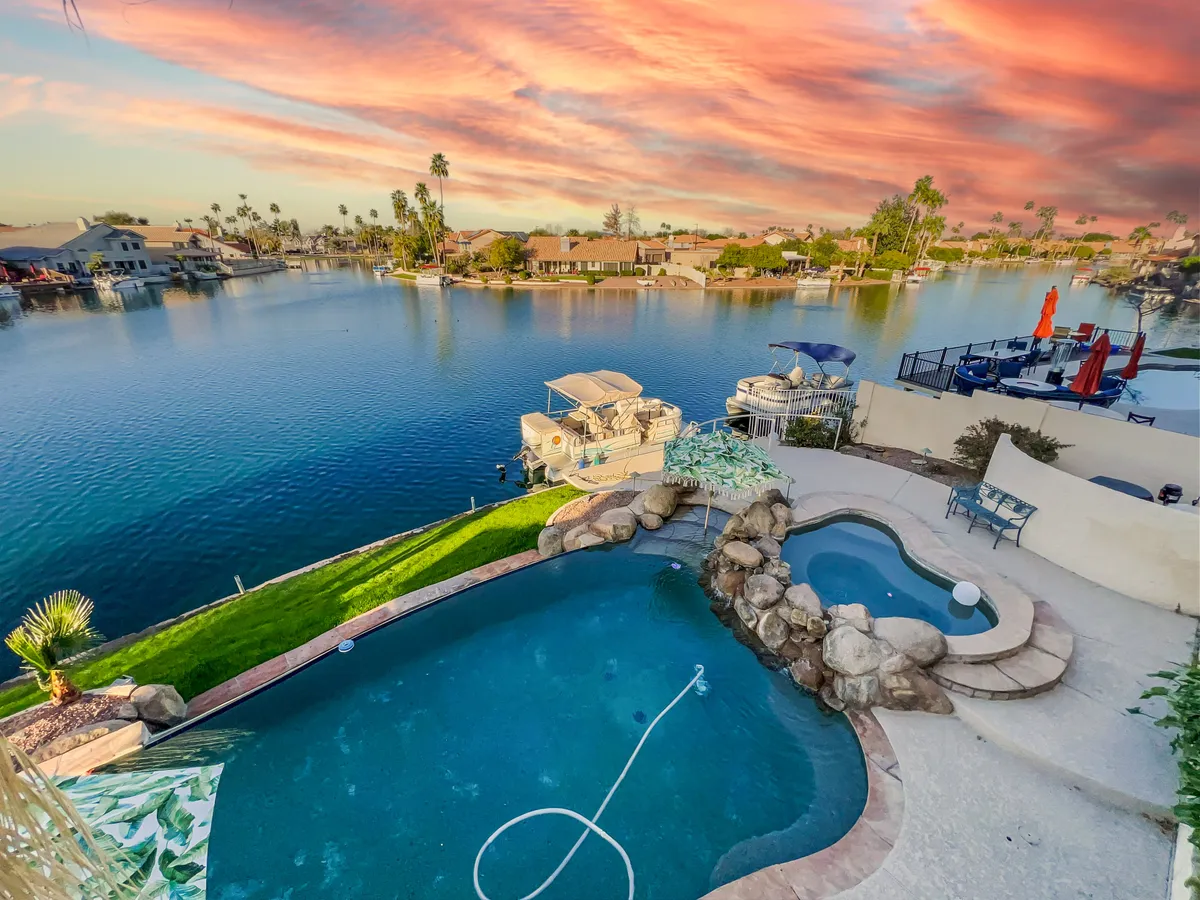 An inviting exterior space showcasing a sparkling swimming pool, waterfront views, and an outdoor seating area set under a sunset sky. The scene exudes relaxation and community, echoing the neighborhood’s recreational appeal and access to water activities.