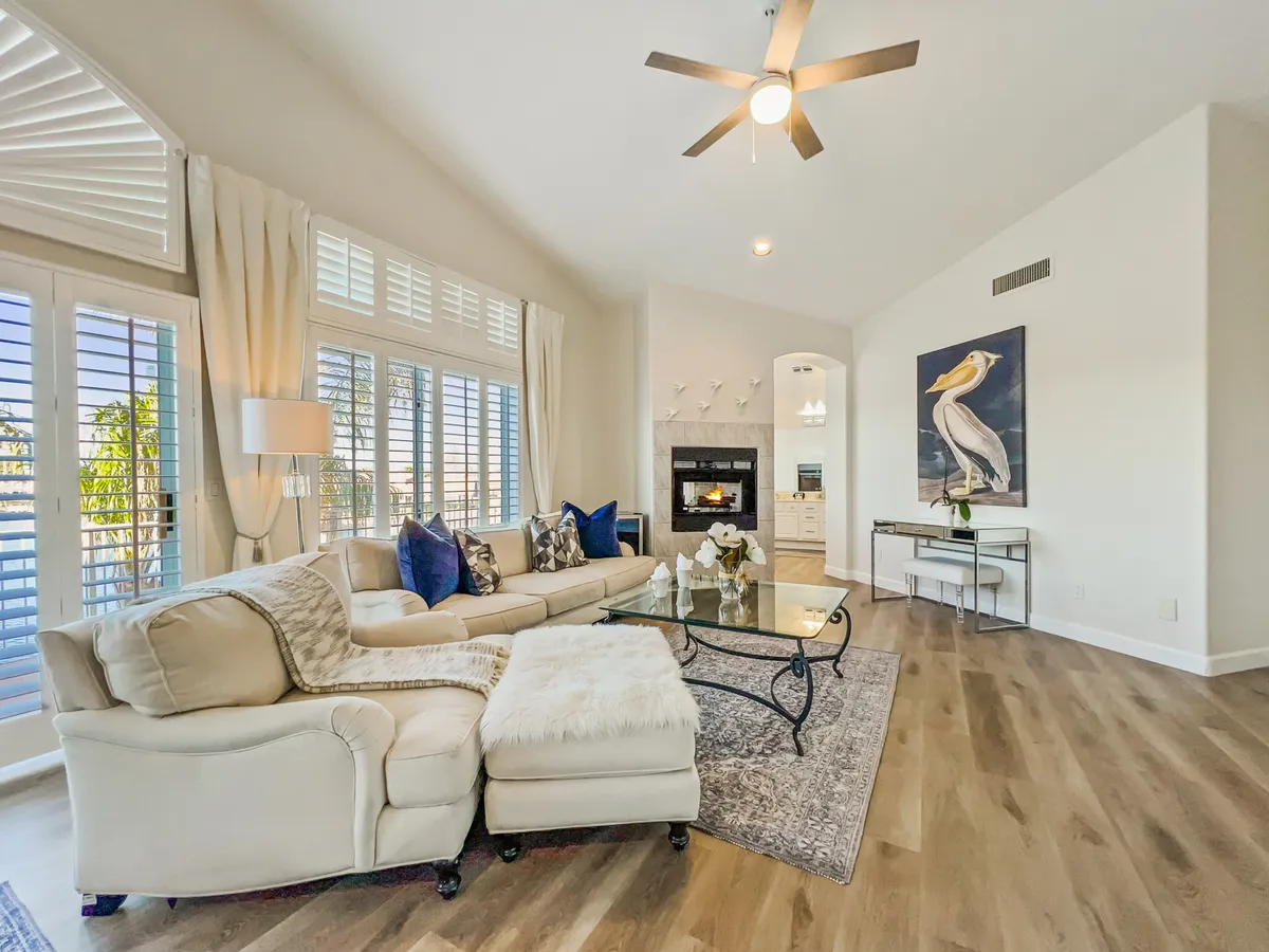 A cozy living area with a comfortable sectional sofa, stylish artwork, a glass coffee table, and a fireplace, offering a relaxed setting for socializing, reading, and gathering with loved ones.