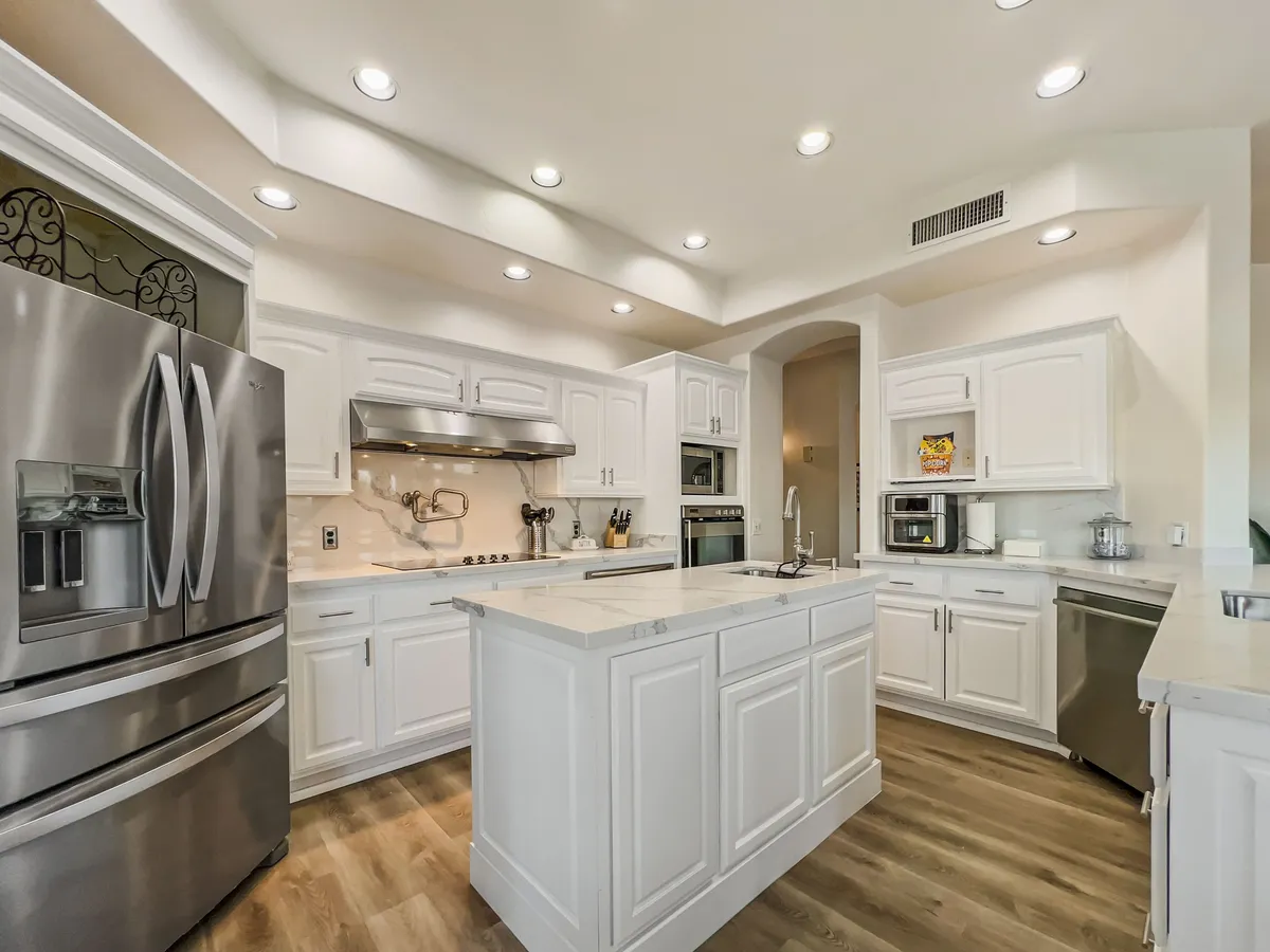 A contemporary kitchen outfitted with sleek modern appliances, a central kitchen island, and crisp white cabinetry. The inviting atmosphere is perfect for baking, hosting brunch, or enjoying a quiet morning coffee. The layout is open and efficient, promoting both effortless meal prep and social connection.