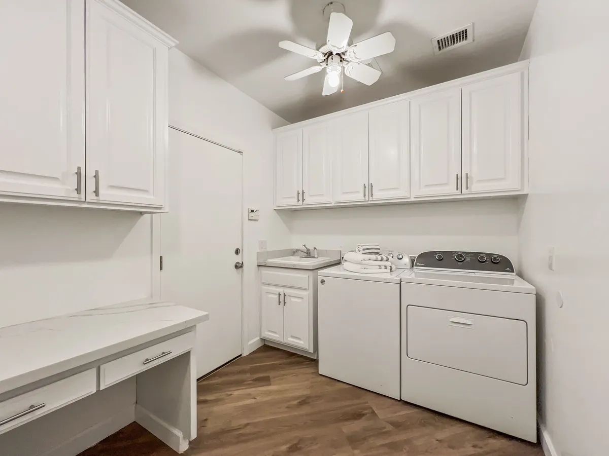 A tidy laundry room equipped with a washer, dryer, sink, and ample counter space, conveying practicality and convenience for extended stays.
