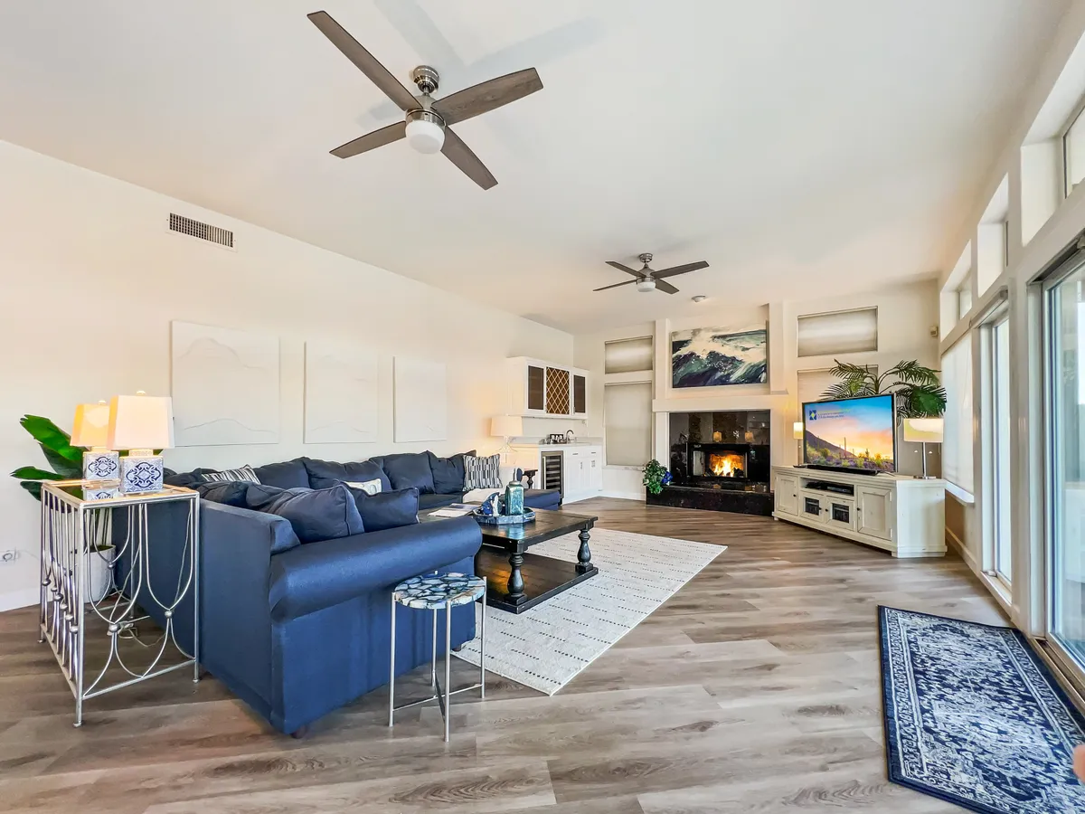 A spacious great room featuring a large sectional sofa arranged around a modern fireplace, with sunlight streaming in and an inviting, cozy atmosphere for family movie nights or intimate conversations.
