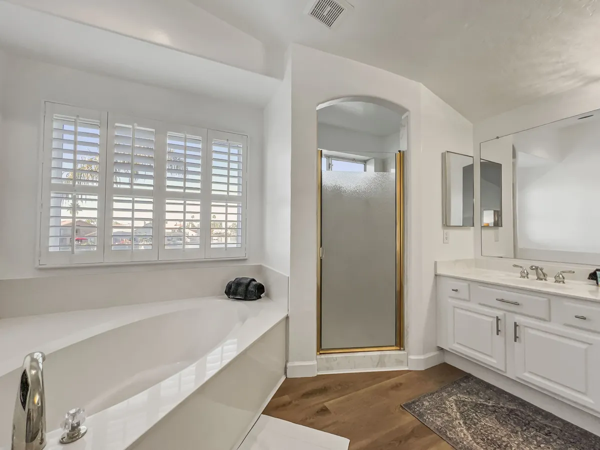 A tranquil bathroom setting with a standalone bathtub, spacious vanity, shower enclosure, and window with shutters. The clean and refreshing atmosphere evokes a spa-like experience, echoing the 'spa-like bathroom' described in the section.