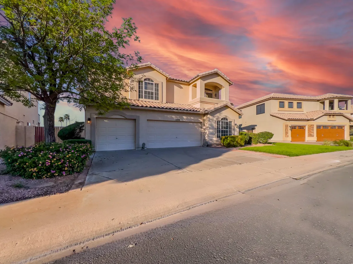 A view of the home's facade featuring a spacious garage, lovely landscaping, and a welcoming porch. The house is nestled within a serene neighborhood, suggestive of a safe, family-friendly environment perfect for evening strolls or neighborhood gatherings.
